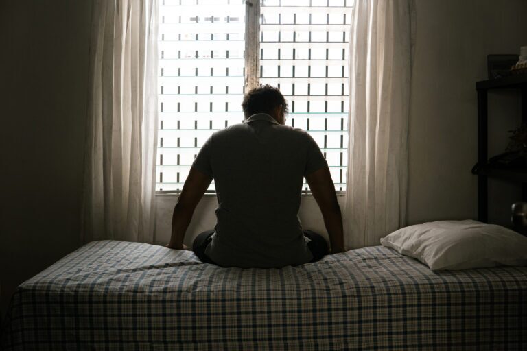 Desperate man in silhouette sitting on the bed alone.