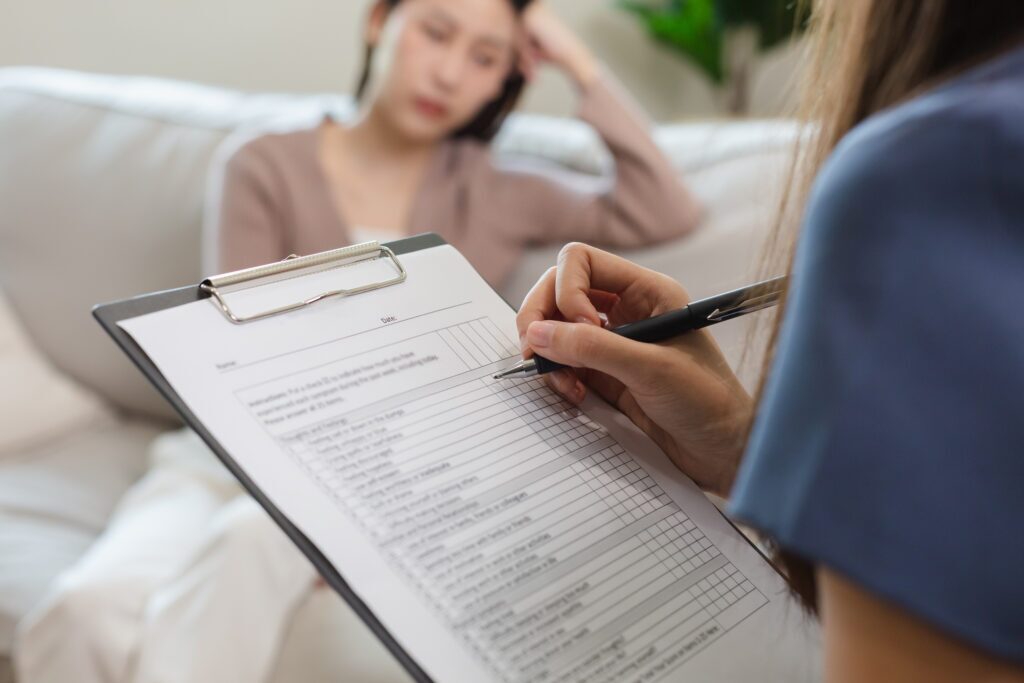 Psychiatrist taking notes examining female patients therapy for mental symptoms and depression. close up hand taking notes on clipboard.